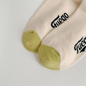 Detail of off-white cotton socks with green toe patch and Fuego letter pattern