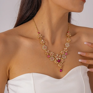 Detail of a vintage golden floral necklace with pink crystals worn by a model