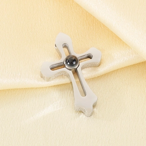 Detailed view of silver cross pendant with black center stone on beige satin fabric