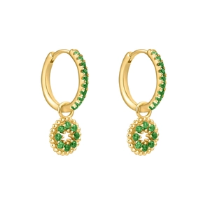 Détail de boucles d'oreilles dorées avec zircons verts et breloques rondes suspendues