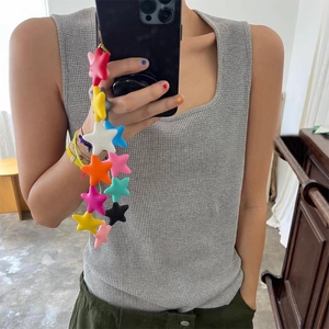 Macro detail of colorful star beaded phone charm strap used in a lifestyle selfie shot