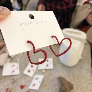 Close-up of red matte heart-shaped hoop earrings on a white display card detail