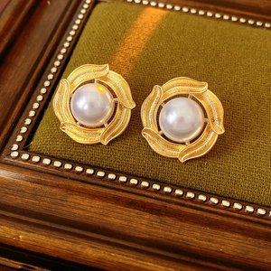 Macro shot of vintage pearl earrings with golden textured base on green velvet tray
