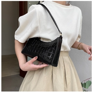 Close-up of black crocodile pattern hobo bag with gold hardware worn on white T-shirt