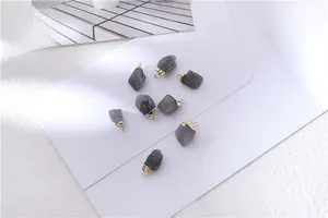 Macro view of dark grey raw crystal pendants with golden metal caps for jewelry making