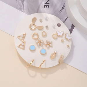 Flat lay of 12 pairs gold earrings set featuring pearls and floral geometric designs
