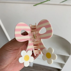 Detail of pink striped butterfly hair claw clip with small daisy flower embellishments