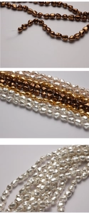 Macro detail of irregular baroque pearl strands in bronze, gold, and white luster