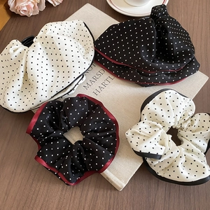 Close-up of retro polka dot scrunchies with contrast wave edges and smooth silk-like texture