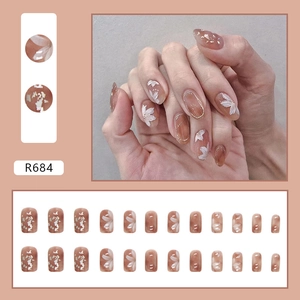 Caramel amber press-on nails with white floral patterns and gold foil flakes in short square