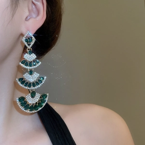 Detail of luxury emerald green drop earrings with gold diamond-encrusted tassel design