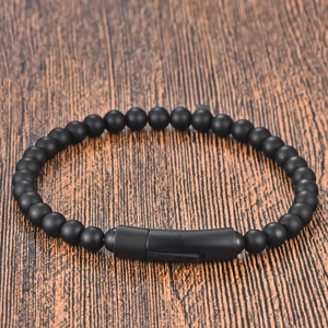 Minimalist matte black beaded leather bracelet for men with magnetic clasp on wood surface