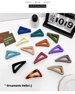 Flat lay of colorful matte triangle hair claws in various shades on a white desk