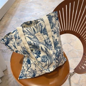 Detail of botanical print canvas tote bag resting on a wooden chair in lifestyle setting