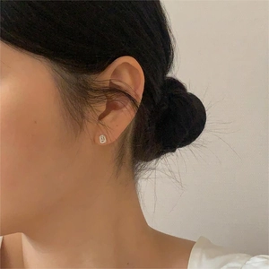 Close-up of minimalist silver geometric stud earring worn on model for scale