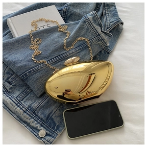 Golden mango acrylic evening clutch with metal chain strap on a casual background