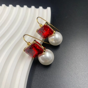 Vintage style gold earrings with square red gemstone and white round pearl on display