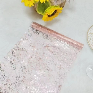 Detailed texture of pink mesh table runner with gold foil crackle pattern on plush white fabric