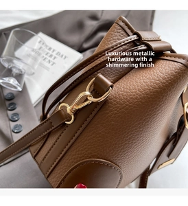 Detail of high-quality golden metal buckle on brown leather bucket bag with litchi texture