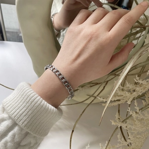 Close-up of silver chain link bracelet worn on wrist with minimalist lifestyle setting