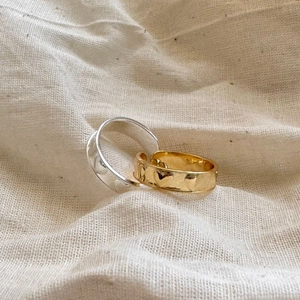 Detailed close-up of S925 silver rings with hammered texture and heart patterns on linen