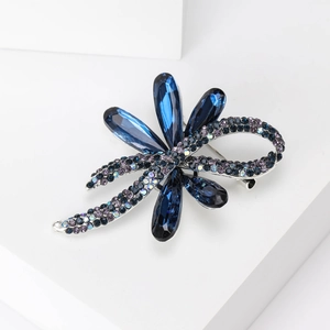 Detailed close-up of a silver bow brooch with blue crystals and purple rhinestones