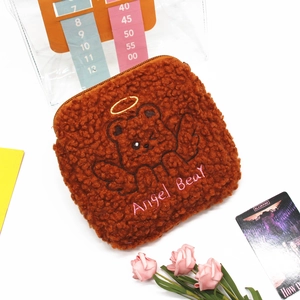 Detail of a brown sherpa fleece plush bag with embroidered angel bear and zipper closure