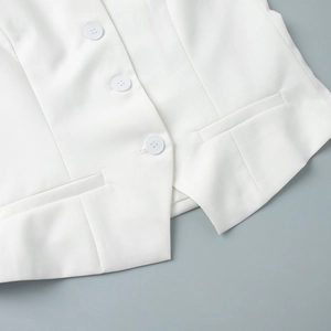 Detail of white vest with resin buttons and asymmetrical hem in woven fabric