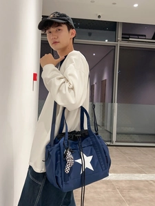 Water-resistant navy blue tote bag with star design and checkered charm shown on model