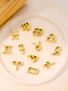 Macro shot of twelve golden zodiac symbol pendants in a ceramic tray for DIY jewelry