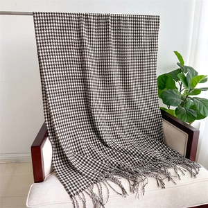 Detailed view of houndstooth scarf with tassels draped on a chair in a home setting