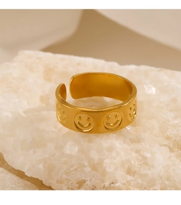 Detailed close-up of a gold-plated smiley face ring on a white decorative stone