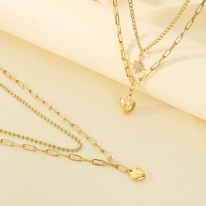 Detailed view of layered gold heart and star pendants on polished titanium steel chains
