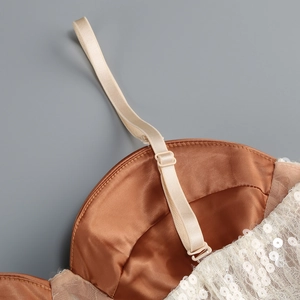 Détail des bretelles réglables et du tissu en maille pailletée d'une robe de soirée française