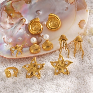 Golden starfish and shell earrings set with pearls and crystals on beach sand