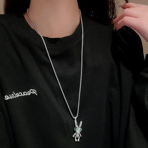 Detail of mechanical rabbit necklace with teal catseye stone on black hoodie