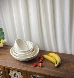 Detail of multi-size round woven rattan fermentation baskets stacked on a wooden table