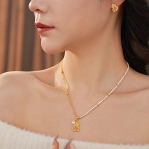 Détail du collier de gourde en or 18 carats et boucles d'oreilles perles sur modèle