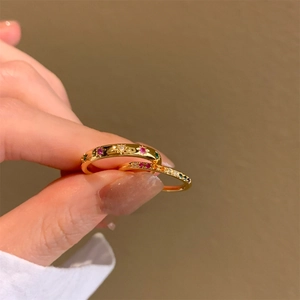 Dettaglio di anelli dorati con zirconi colorati e stella a sei punte incisa a mano