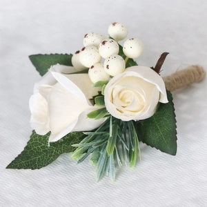 Wedding boutonniere with off-white roses and green leaves on white textured fabric