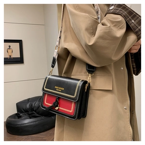 Detail of red and black leather crossbody bag with decorative wide woven shoulder strap