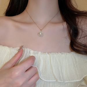 Gros plan du collier doré avec pendentif en perle et halo de zircons sur le cou