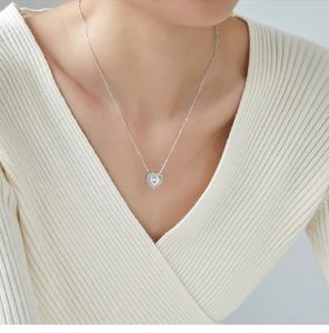 Close-up of heart-shaped silver necklace with pavé zircons worn by a model