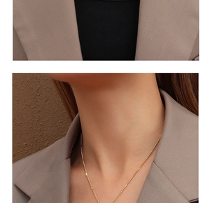 Gros plan d'un collier chaîne en or porté sur le cou avec un blazer marron chic