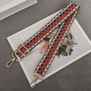 Detail of red and black geometric woven purse strap with gold metal swivel snap hooks