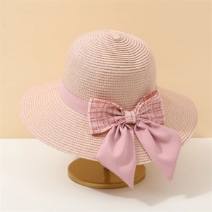 Close-up of pink straw sun hat featuring elegant plaid tweed and satin bow details