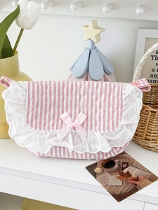 Detail der gesteppten Schminktasche mit rosa Streifen, Spitze und einer Schleife