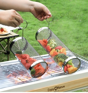 Detail of cylindrical stainless steel BBQ mesh baskets with vegetables on an outdoor grill