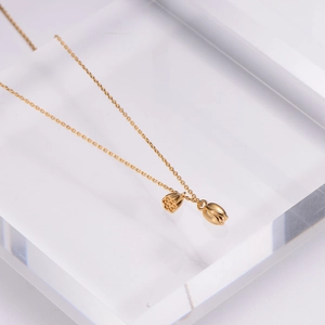 Gold-plated lotus flower and seed pod pendant necklace on a transparent stand