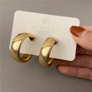 Close-up of chunky gold C-shaped hoop earrings with 925 silver posts on a display card